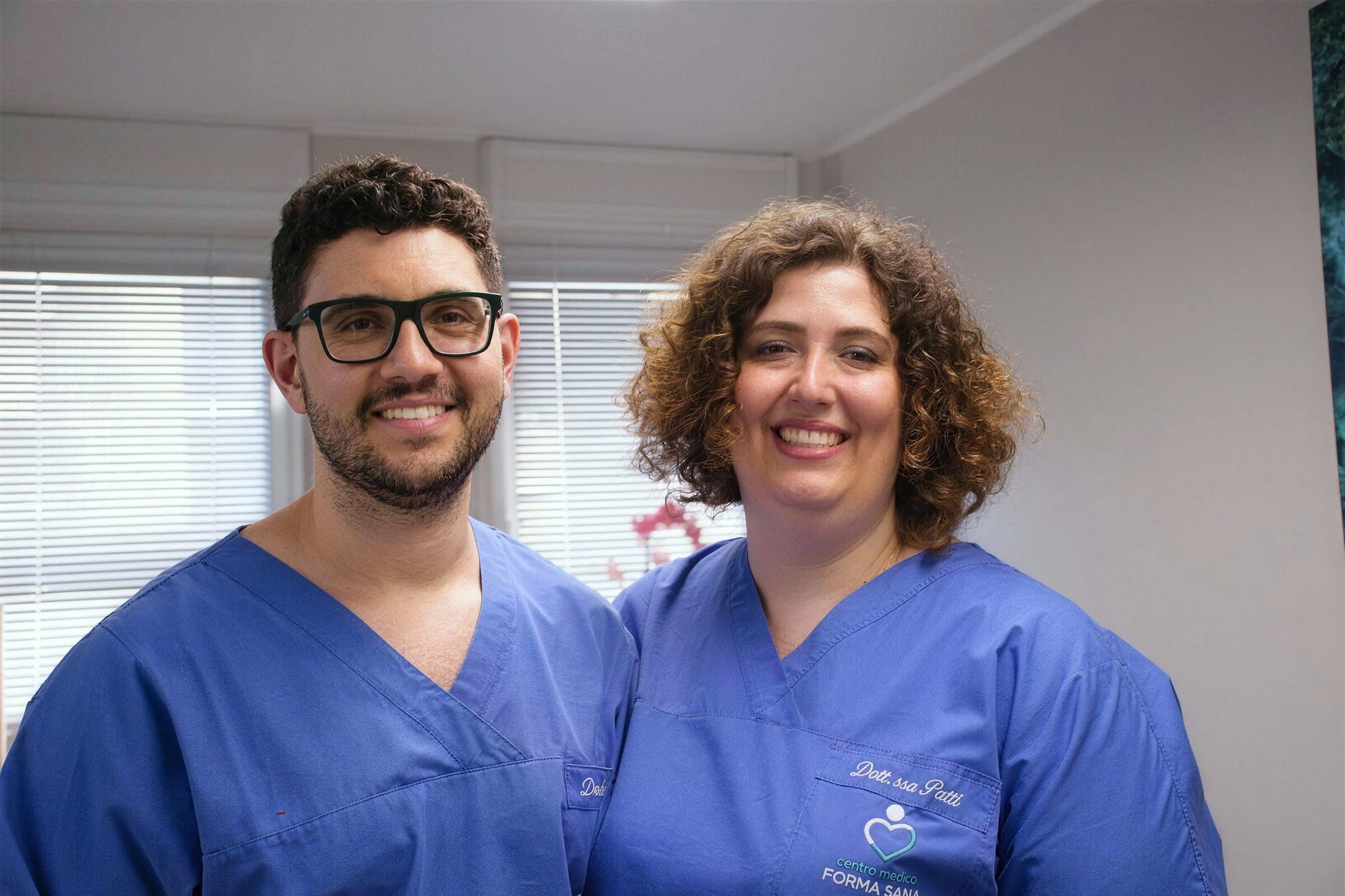 Pietro Carlomagno e Alessandra Patti, in divisa da ambulatorio, sorridono nello studio