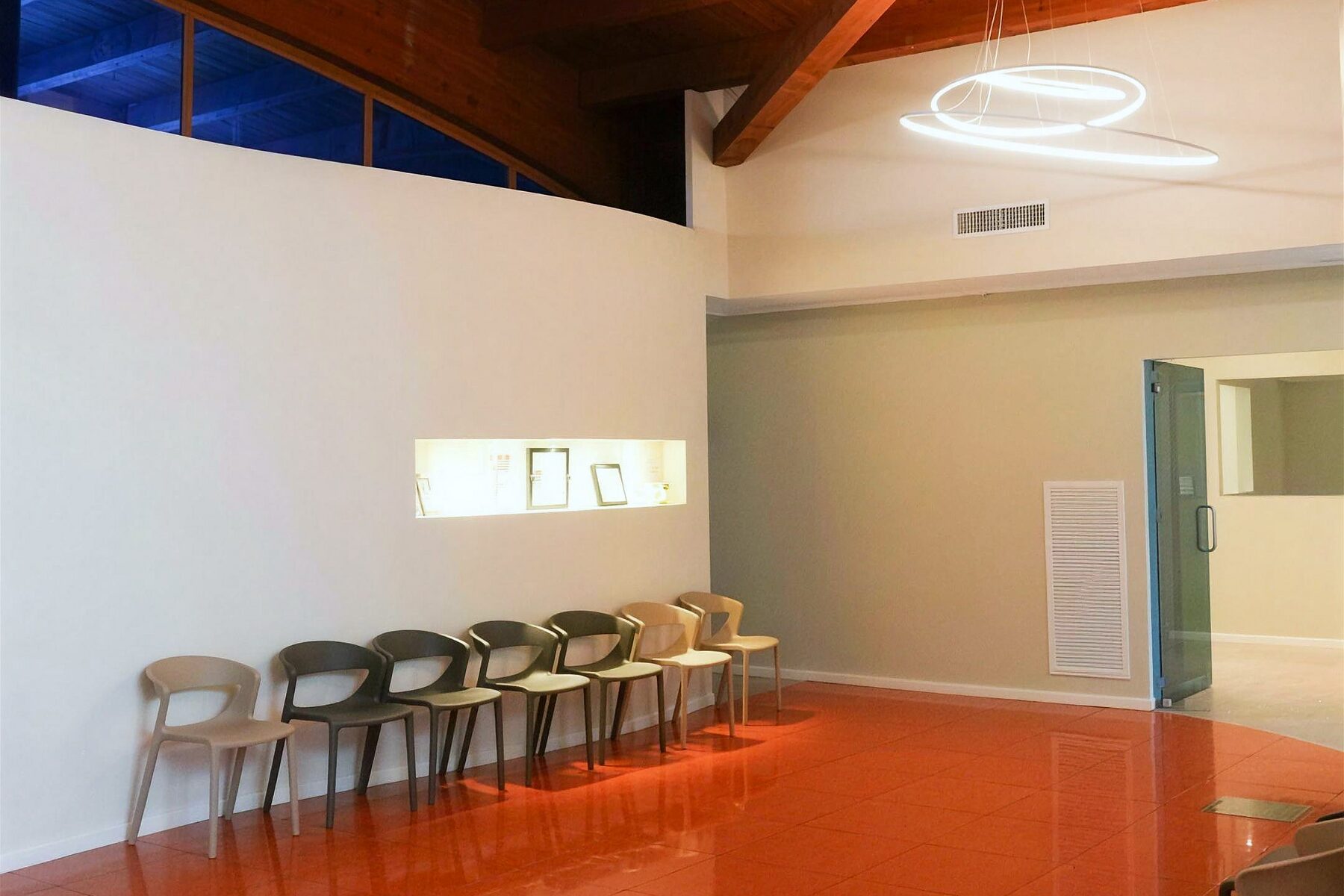 La sala d'attesa del centro, con le sedute in fila sotto la parete bianca e il pavimento color terracotta