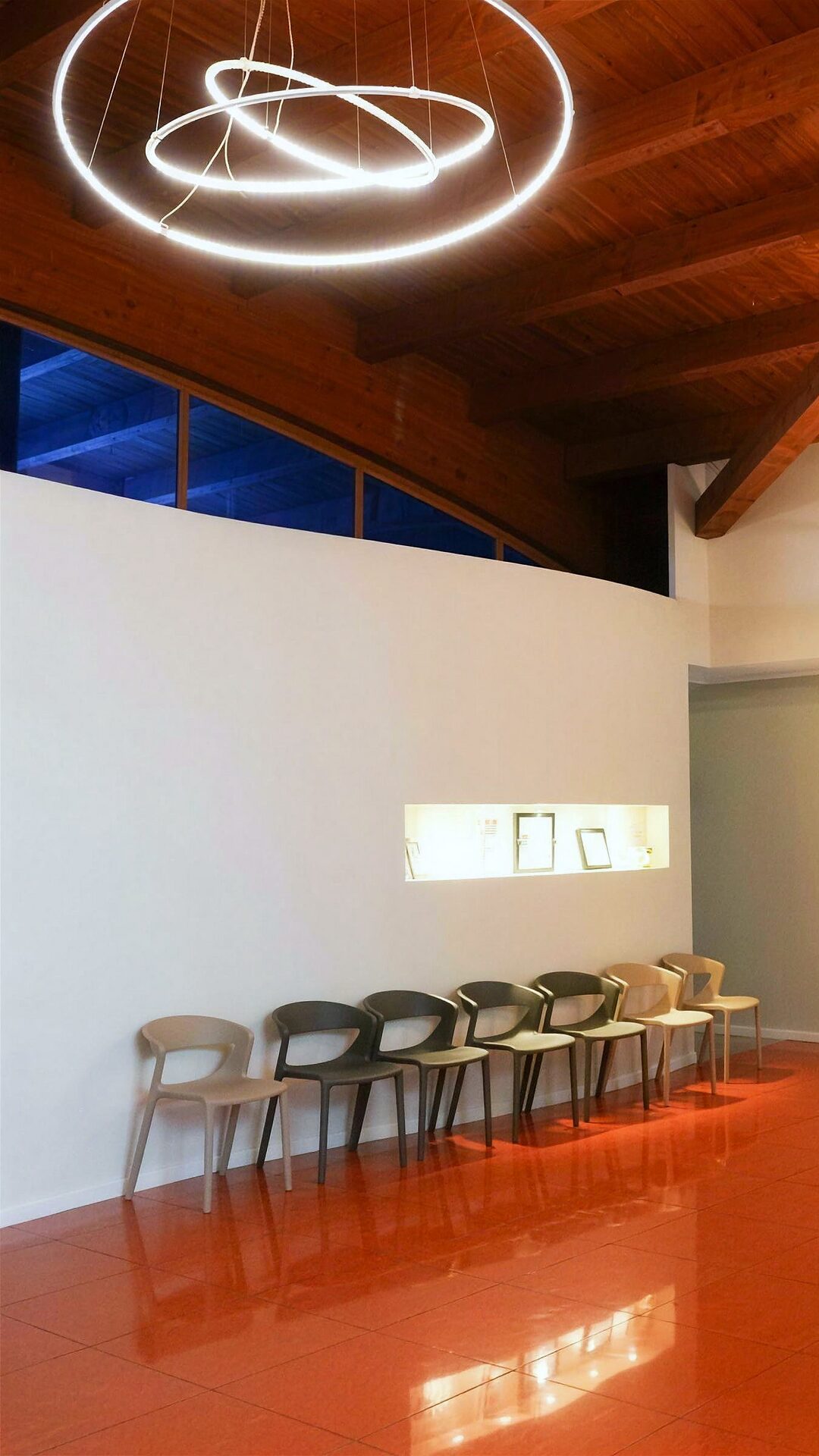 La sala d'attesa del centro, con il soffitto in legno, la luce ad anello e il pavimento color terracotta