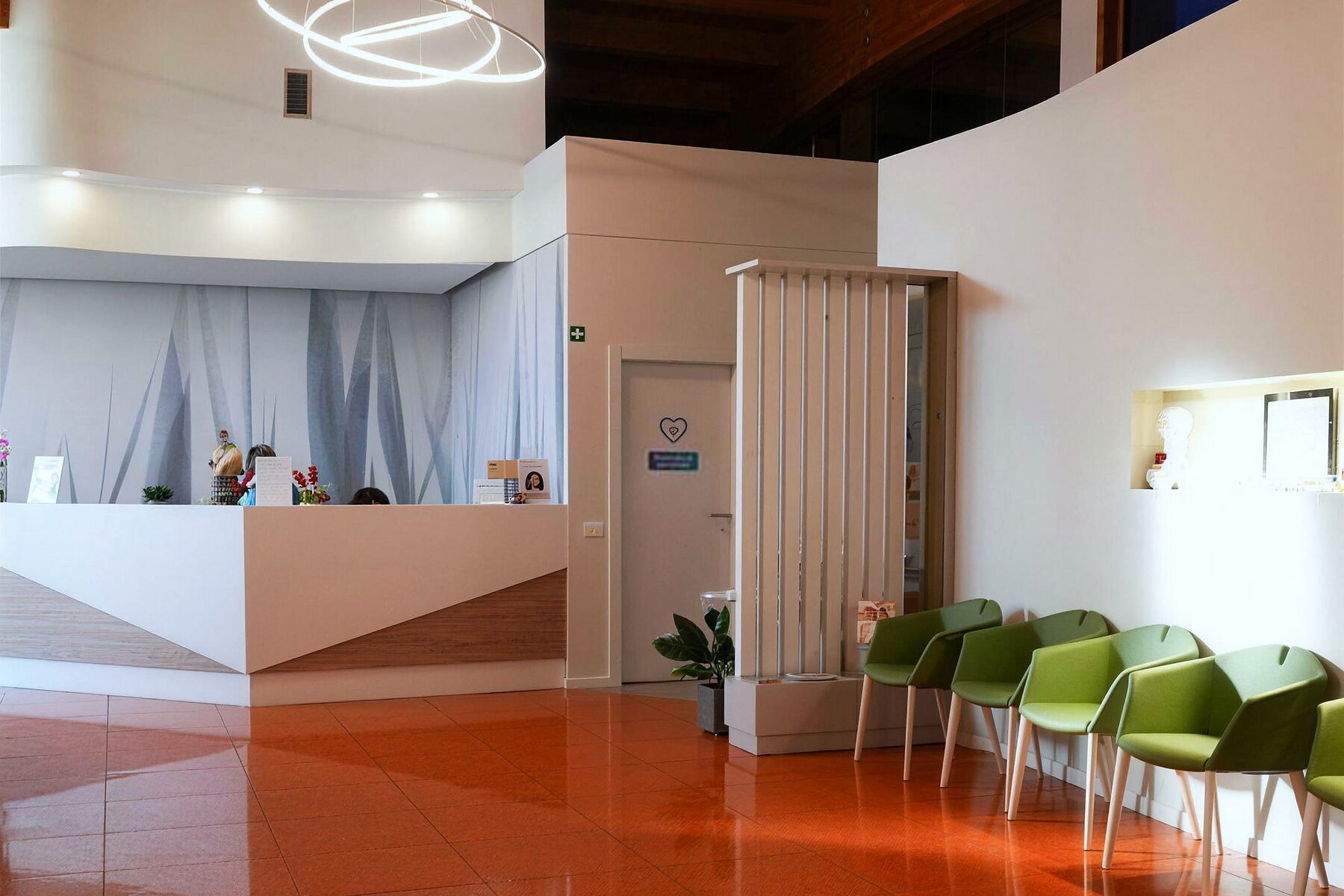 L'ingresso del Centro Medico Forma Sana: il bancone dell'accoglienza, le sedute verdi e il pavimento color terracotta